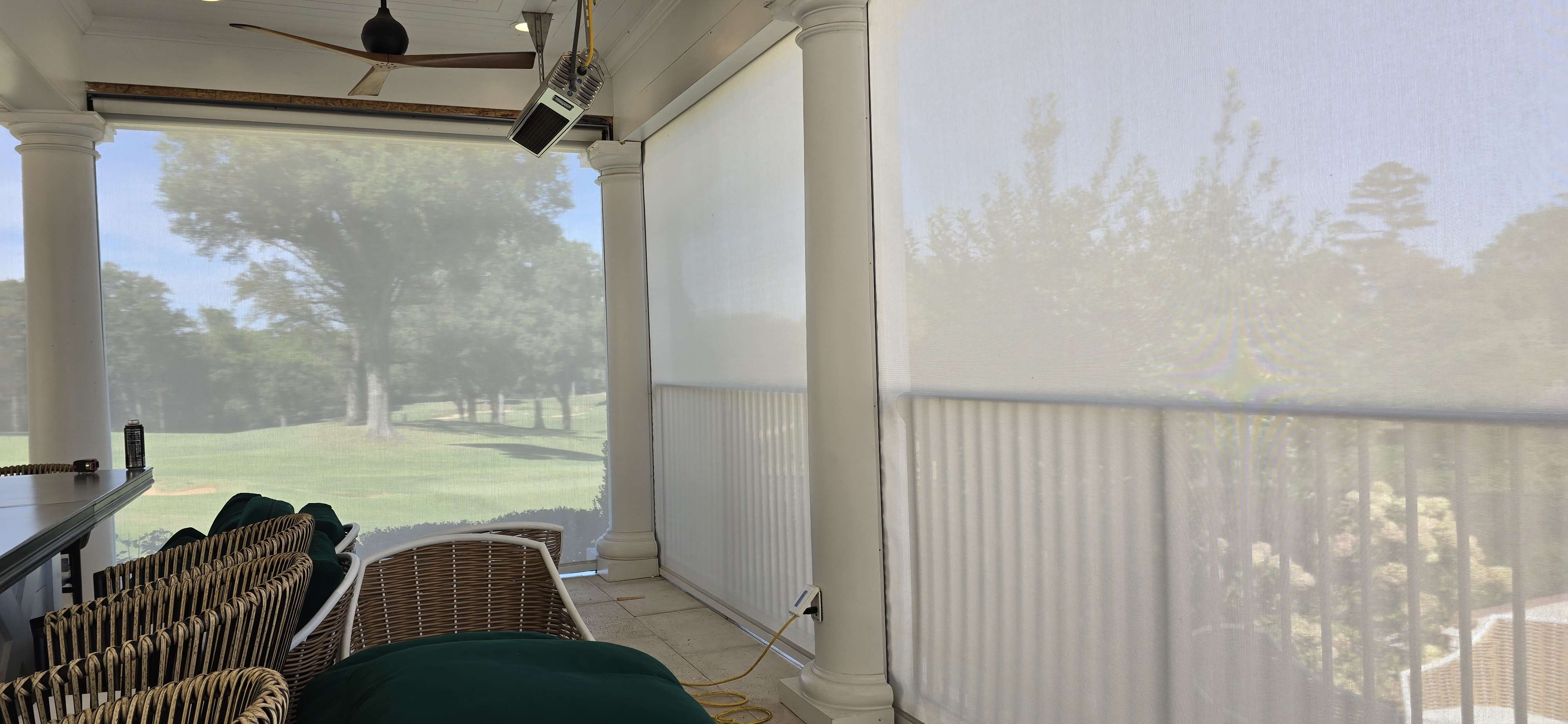 Motorized exterior solar screens on a covered porch with golf-course views