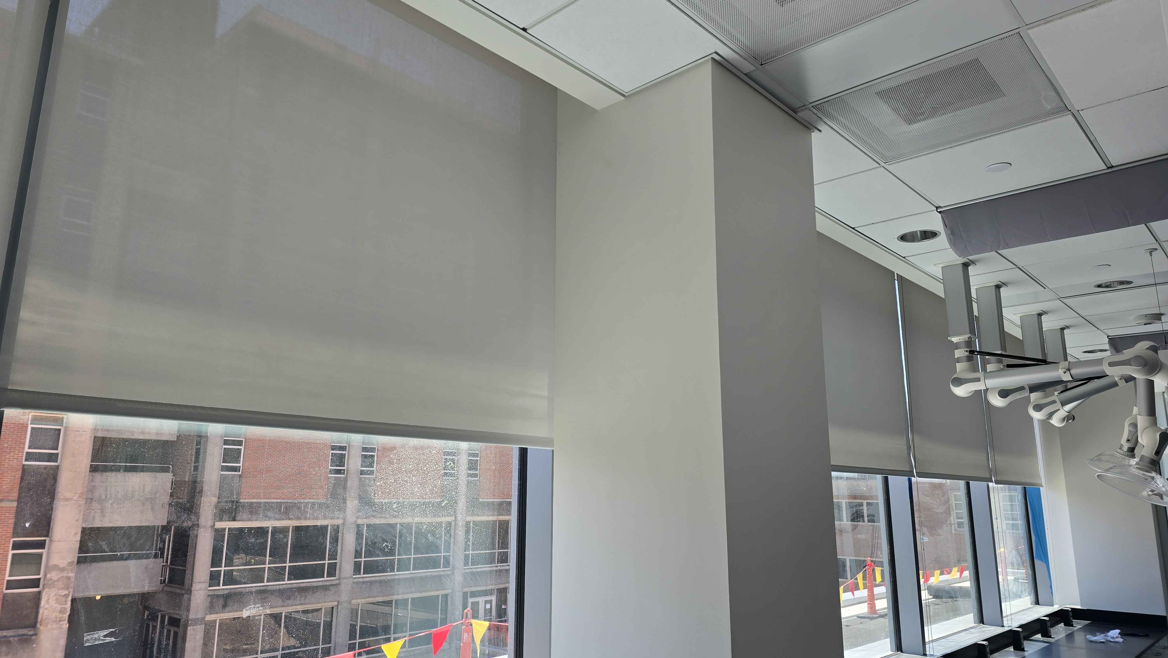 Roller shades on floor-to-ceiling office windows with a downtown view